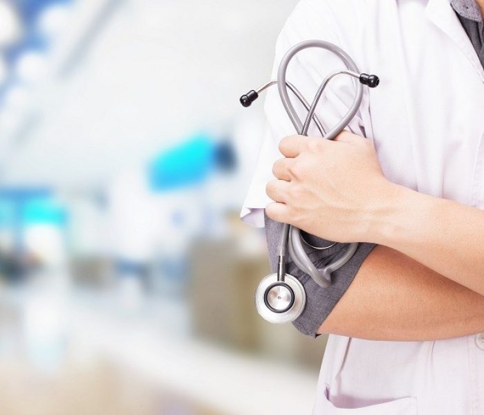 Doctor with a stethoscope in the hands and hospital background.